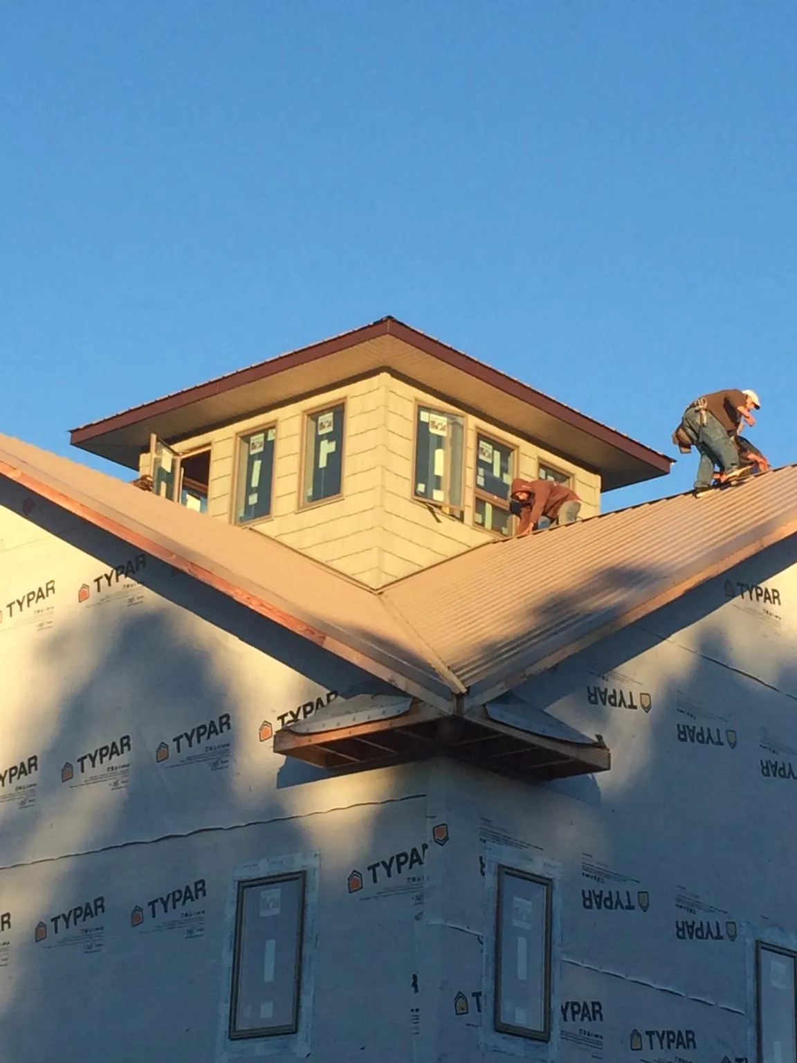 Roofers working around a rooftop cupola on a new metal roof at sunset — Roof Waterproofing in Manhattan by Roofing Brothers